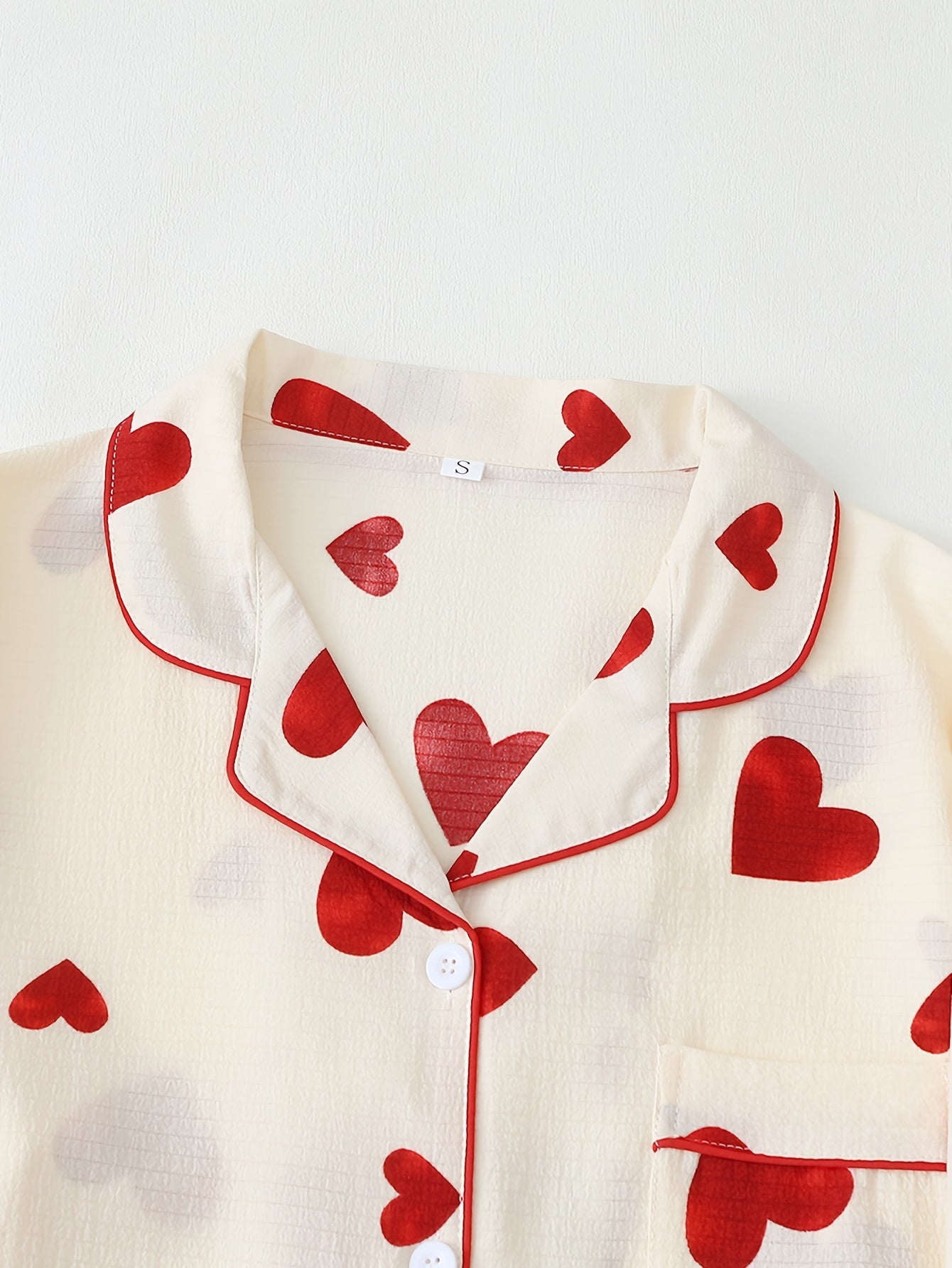 Red heart print pajama set for women with long sleeves, lapel collar, and comfortable fabric made of 95% polyester and 5% elastane. Suitable for all seasons.