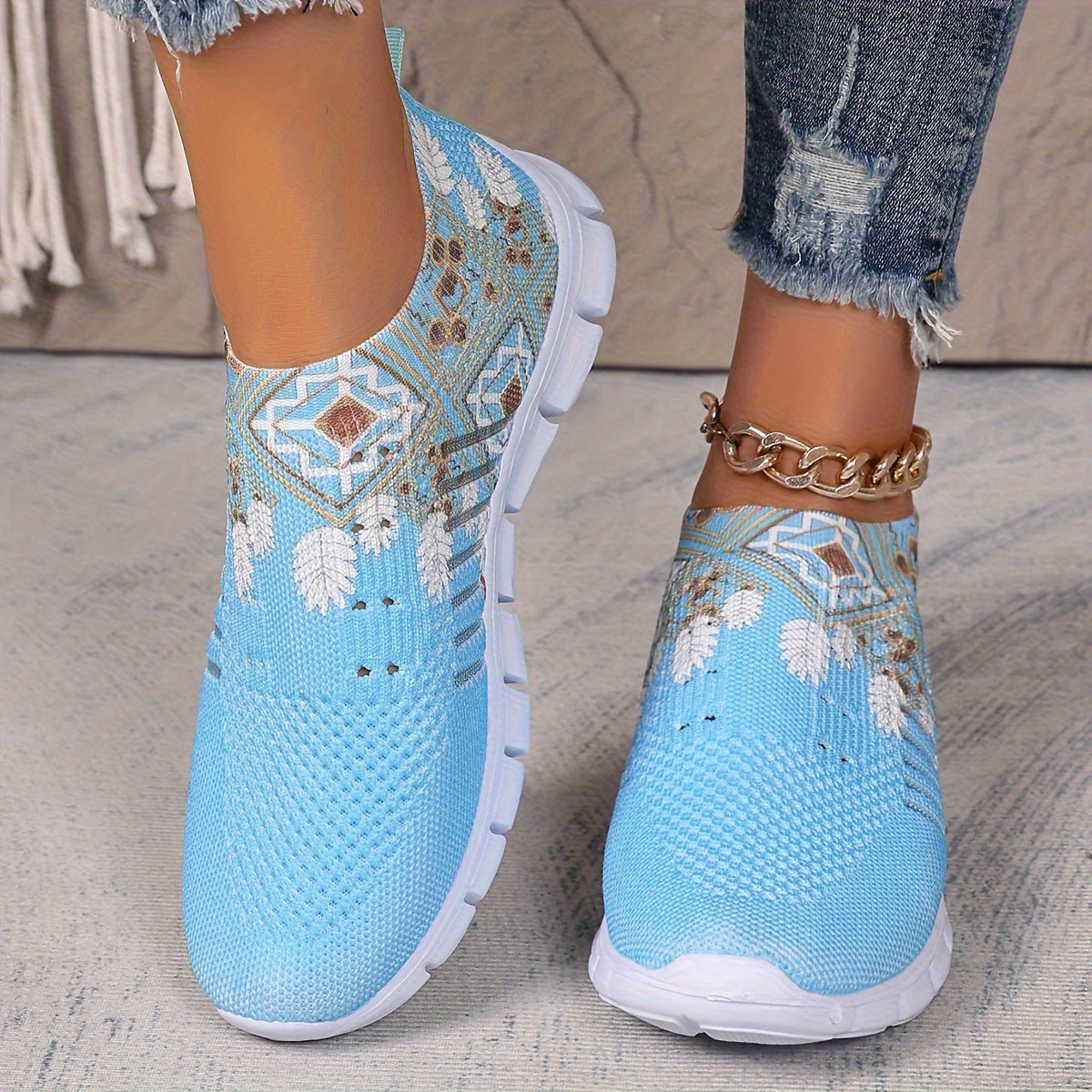 Women's casual slip-on sneakers in blue knit fabric with white floral and geometric patterns, featuring a lightweight EVA sole and breathable low-top design. Perfect for everyday wear with