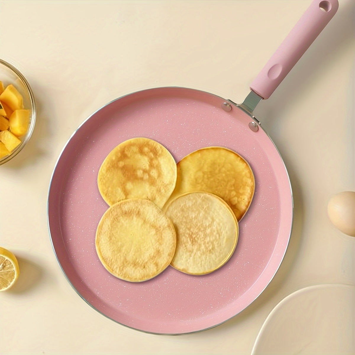 Non-stick aluminum frying pan with pink mica stone finish and wooden handle. Dishwasher safe and compatible with electric coil stoves. Perfect for cooking pancakes and eggs without the need for electricity.