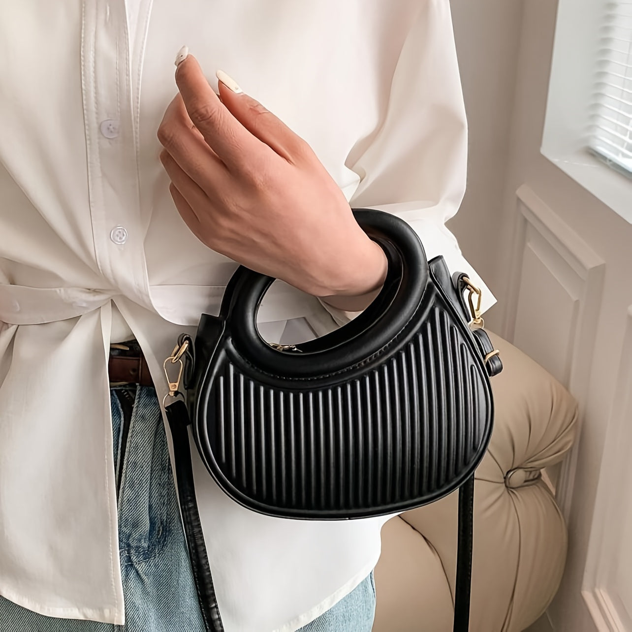 Chic black crossbody bag with embossed stripe pattern and golden-tone hardware, versatile for everyday use with a luxury look.