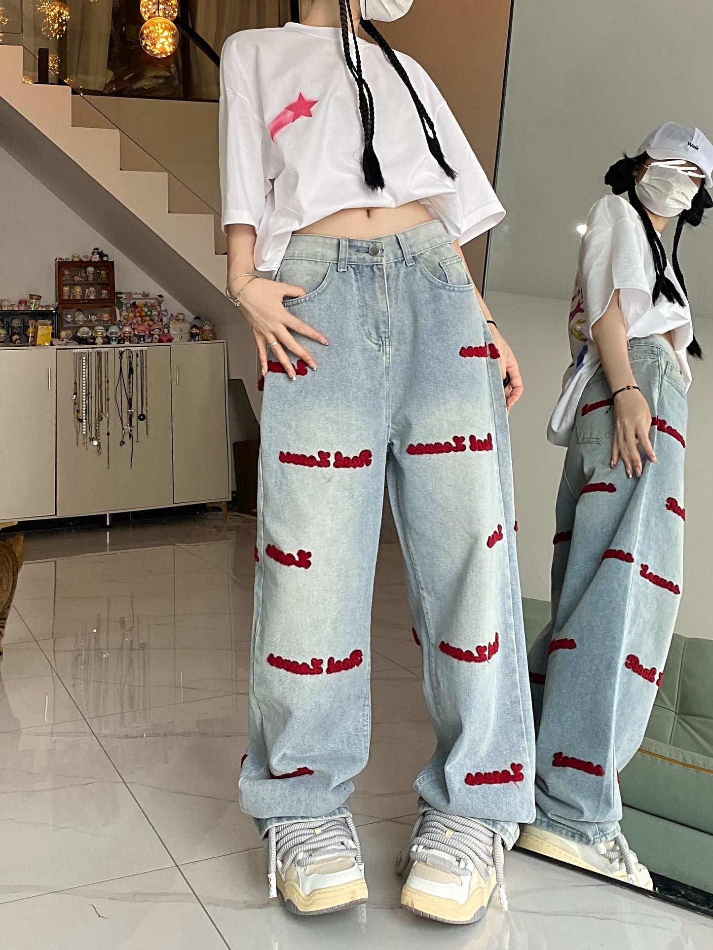 Women's denim jeans with red embroidered lettering, stretch fabric, regular fit, button closure, and washed denim detail. Casual style suitable for all seasons.