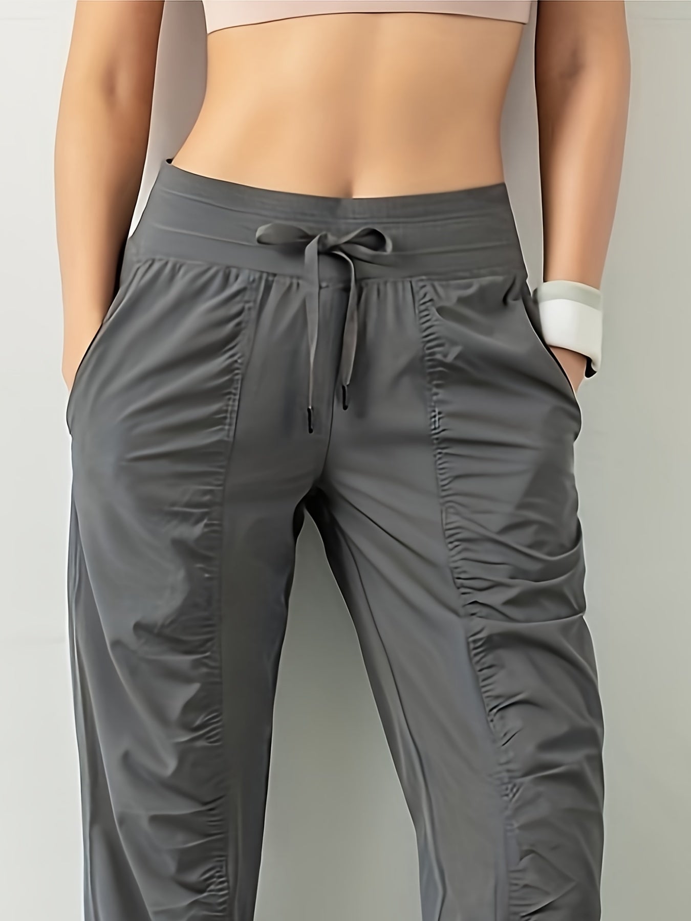 Women's solid color sports pants with drawstring waist, quick drying material, and side pockets for casual comfort.