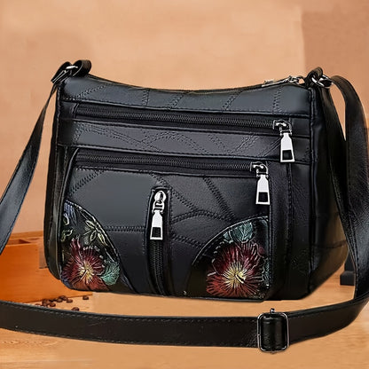 Men's fashion shoulder bag with large capacity, soft faux leather, floral embroidery, zipper closure, and casual messenger style.