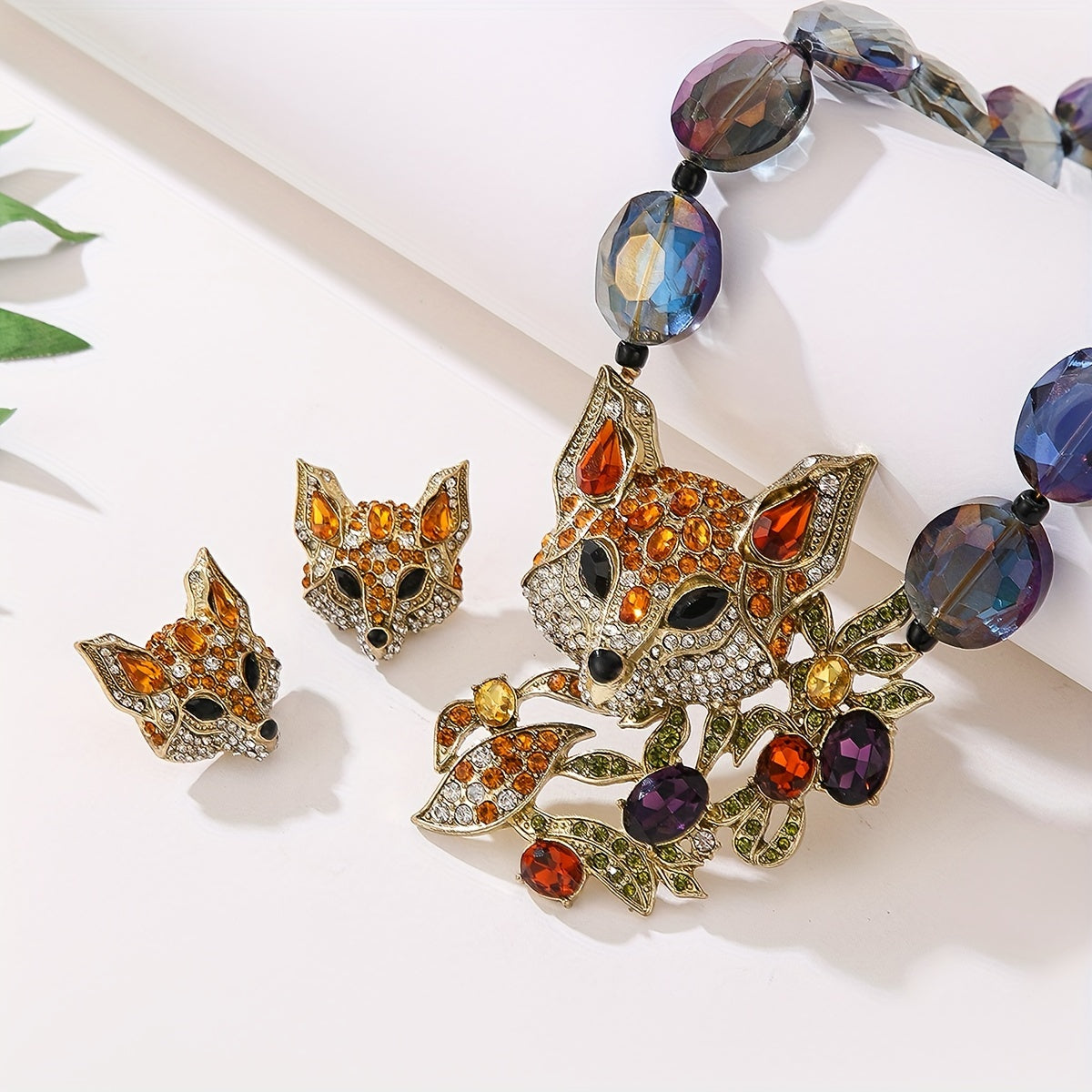 This luxury and exquisitely designed jewelry set features a pendant necklace and earrings adorned with inlaid water diamonds, fox leaves, and colorful acrylic beads. The set is elegant and fashionable, making it the perfect gift for women. It is ideal