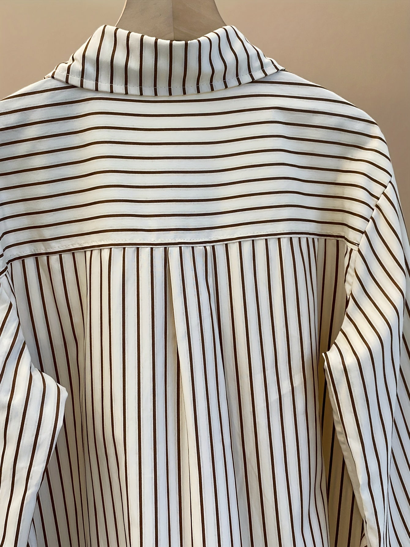 Striped blend shirt for women, with loose fit and ruffled hem detail. French-inspired chic look, perfect for casual wear.