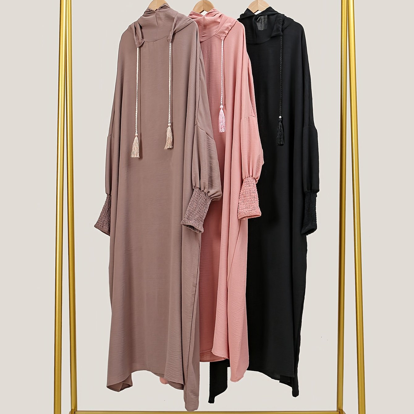 Elegant black abaya with batwing sleeves, drawstring hood, and loose fit. Versatile minimalist style for all seasons. Made of polyester.