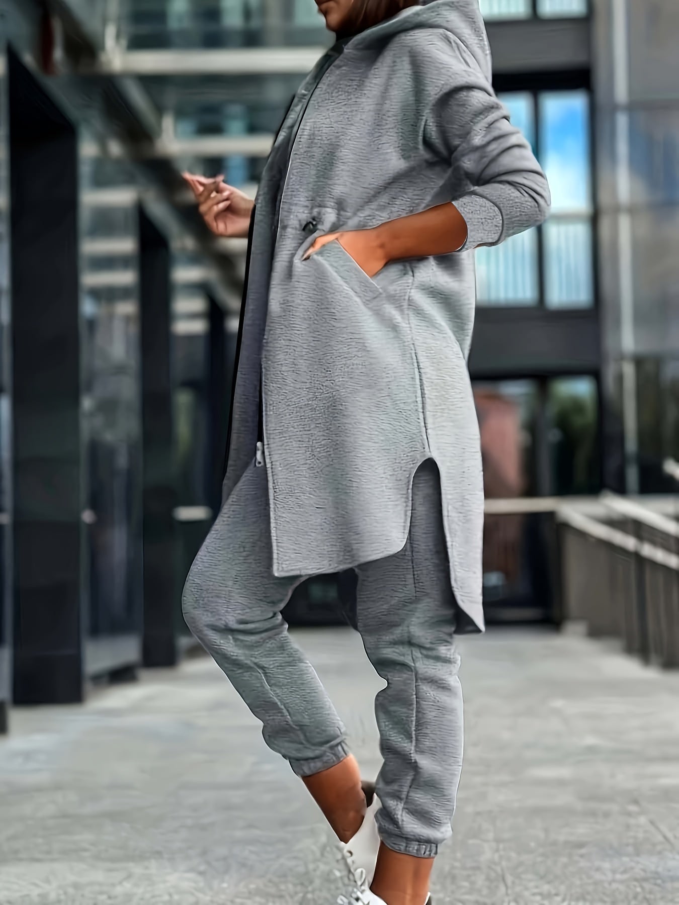 Heather Gray hoodie and jogger set for plus size women. Features zip-up long sleeve top with asymmetrical hem and drawstring pants. Made of a polyester blend and machine washable.