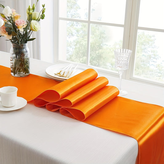 Luxurious polyester satin table runner in vibrant orange color for formal events and stylish home decor. Ideal for weddings, birthday parties, and banquets. Features strong drape and shine, soft smooth fabric, and elegant table setting. Sophisticated and