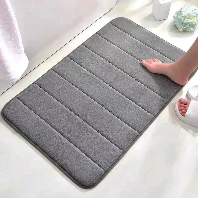 Soft polyester blend bath mat in plush dark gray stripes, featuring a non-slip PVC backing for added safety. Easily machine washable for convenience, this rectangular mat is perfect for adding comfort to your bathroom décor.