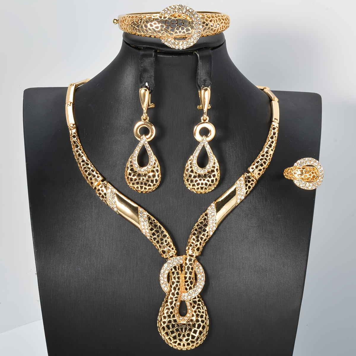 ZEADEAR presents a sophisticated gold-tone jewelry set featuring geometric cutouts. This luxurious collection includes a stunning Y-shaped necklace, bracelet, earrings, and ring, ideal for weddings and parties.