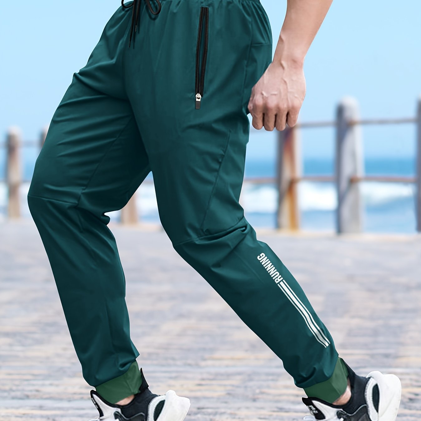 Men's solid color cuffed sports pants made of 100% polyester with moisture-wicking properties. Features a drawstring waist, loose fit, and quick-dry technology for various activities and