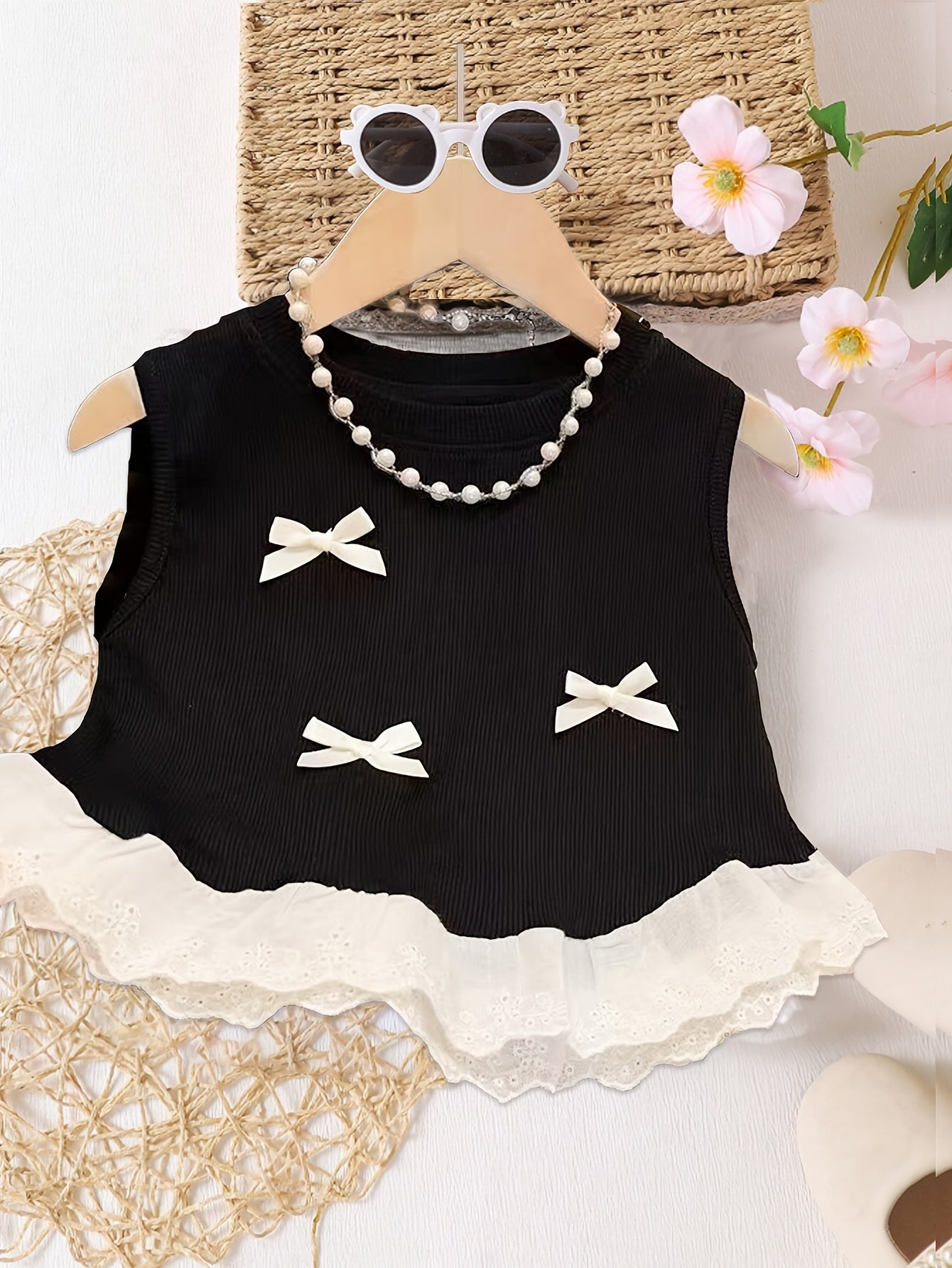 Girls' summer camisole with lace trim, bow decoration, ruffle hem, and sweet top design.