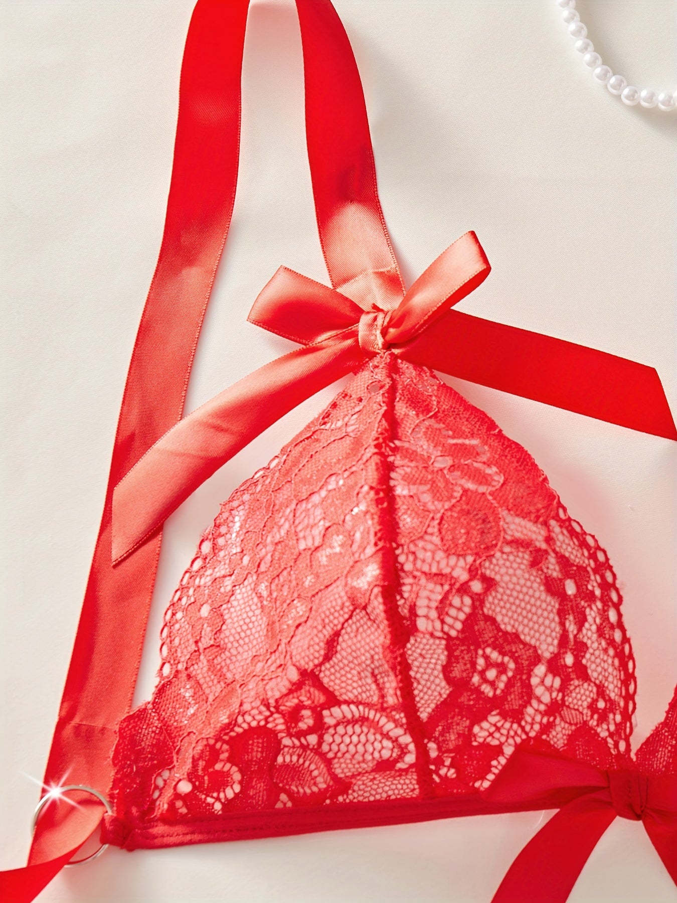 Red lace lingerie set with floral design and bow decorations includes bra, thong, mini skirt, and stockings for a sexy look.