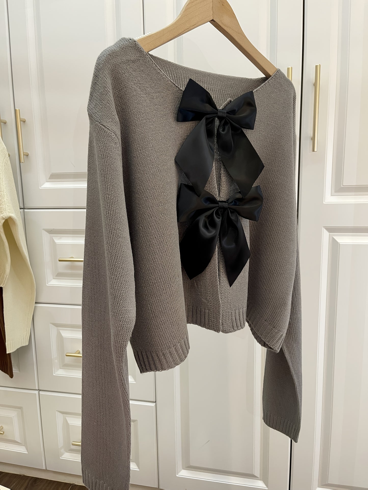 Stylish women's lightweight acrylic knit cardigan with large bow tie, perfect for spring and fall. White with black bow detail.