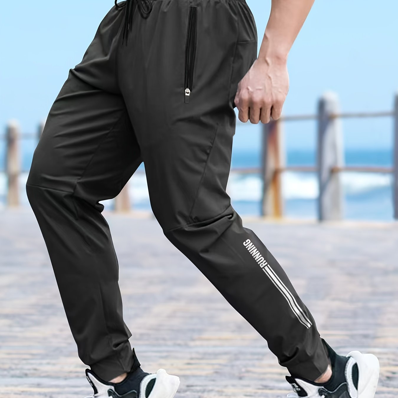 Men's solid color cuffed sports pants made of 100% polyester with moisture-wicking properties. Features a drawstring waist, loose fit, and quick-dry technology for various activities and