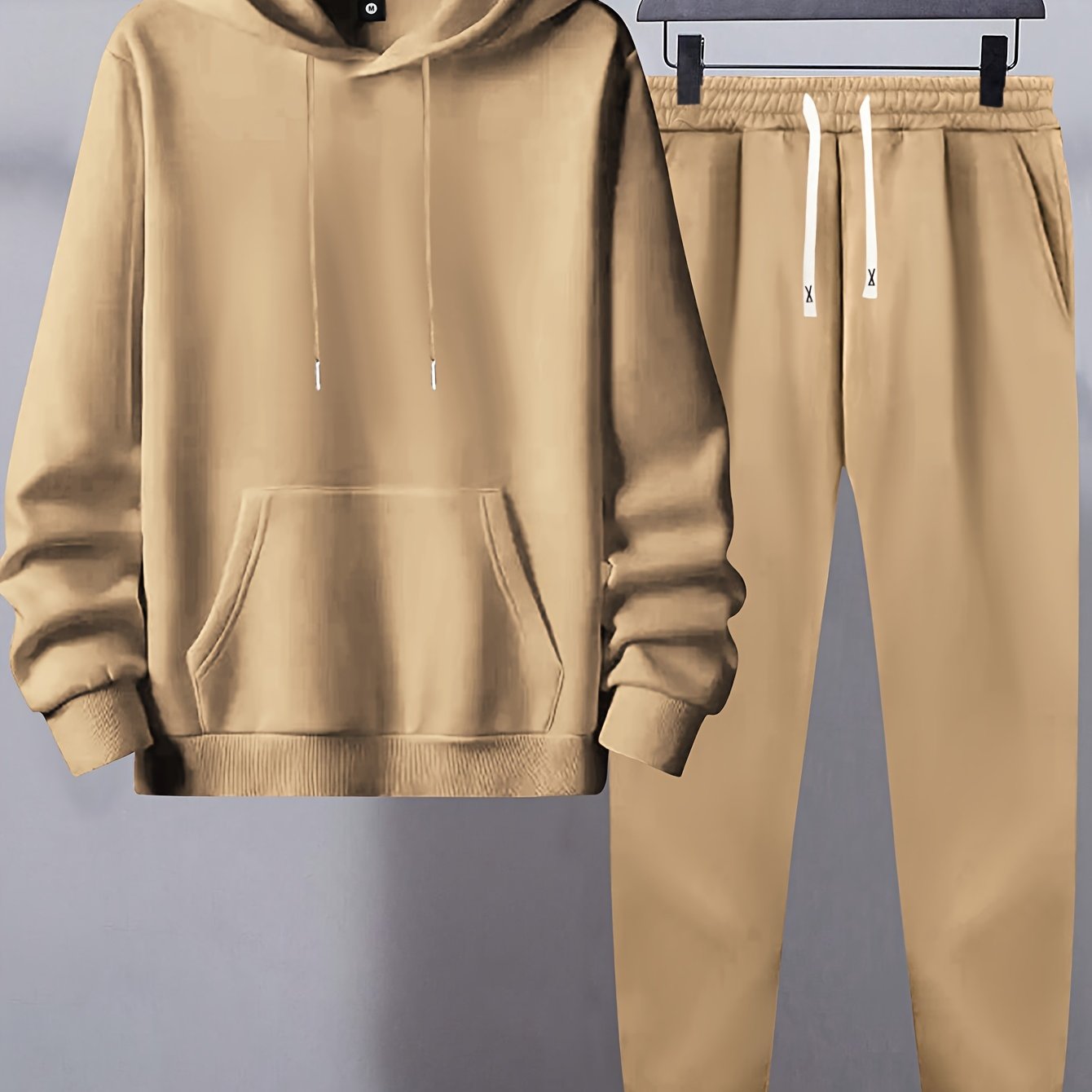 Men's basic polyester sweatsuit set includes a solid color hooded sweatshirt and drawstring joggers with pockets. Made of knit fabric with slight stretch, it has long sleeves and a regular