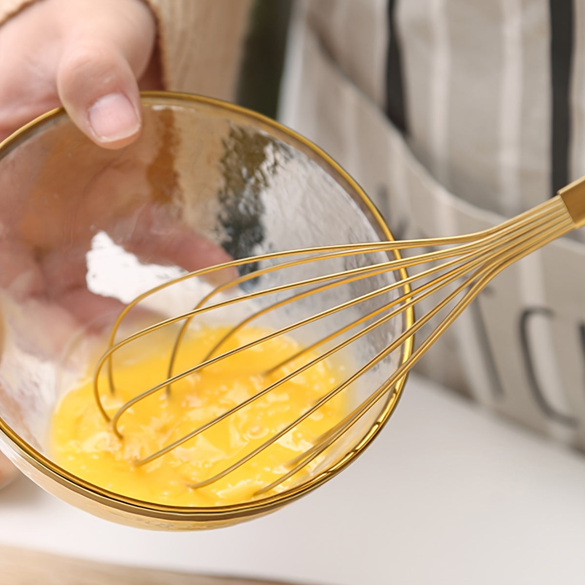 Golden Stainless Steel Egg Whisk is a versatile baking tool that is perfect for cooking in nonstick cookware. This heat-resistant kitchen whisk can be used for mixing, whirling, foaming, and stirring food.