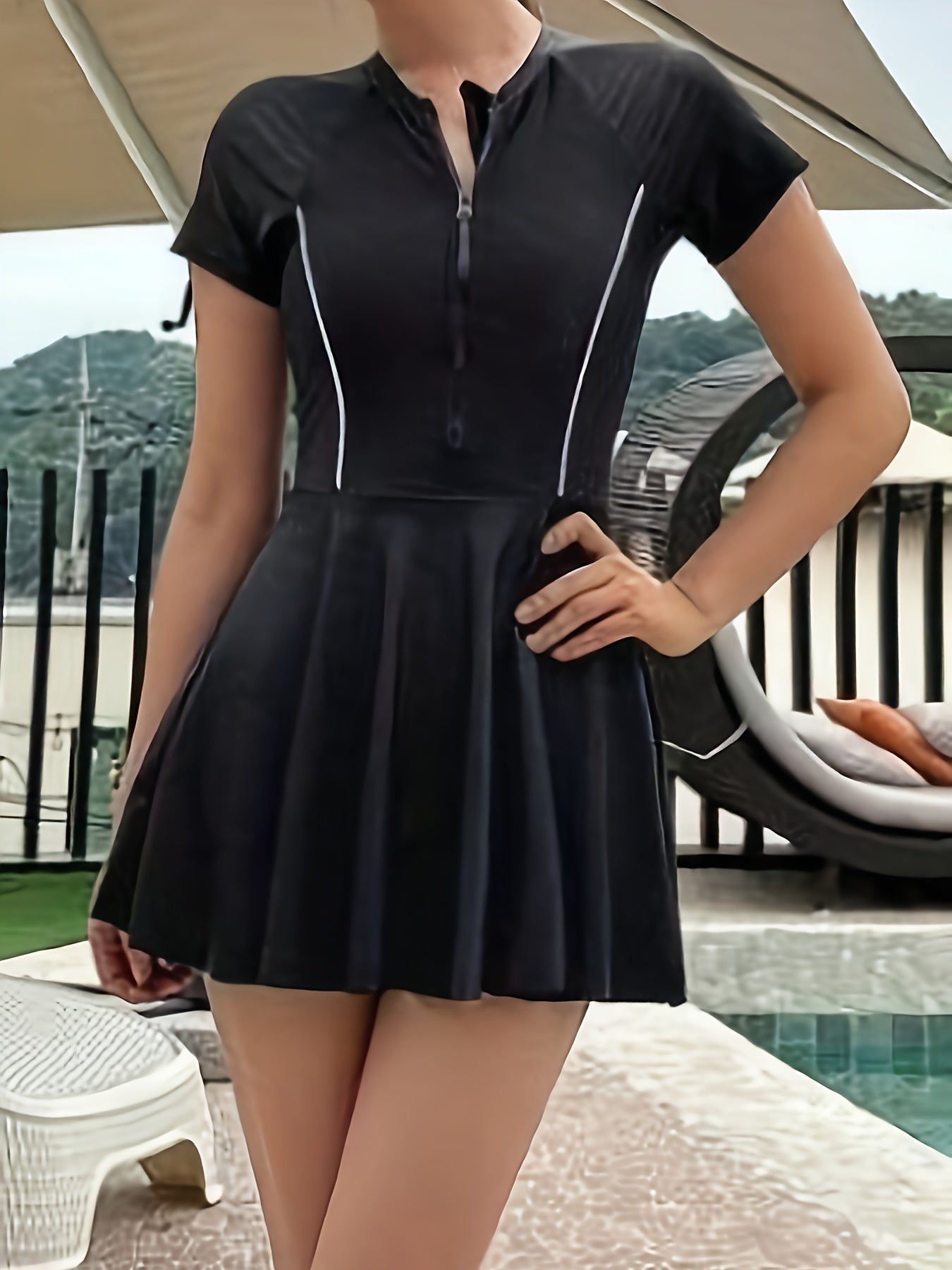 Sporty black one-piece swimsuit for women with zipper detail, made from high stretch nylon/elastane blend. Features short sleeves, round neck, and non-transparent fabric suitable for