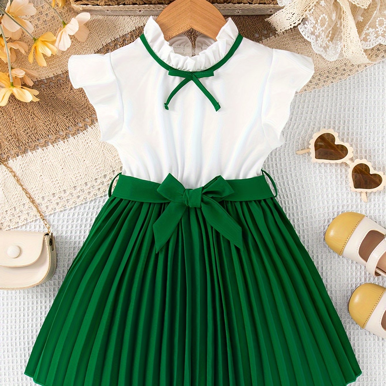 Girls' summer dress with polyester knee-length pleated skirt, stand collar, sleeveless ruffle trim, and bow detail. Features a dressy loose fit with belt for casual outings.