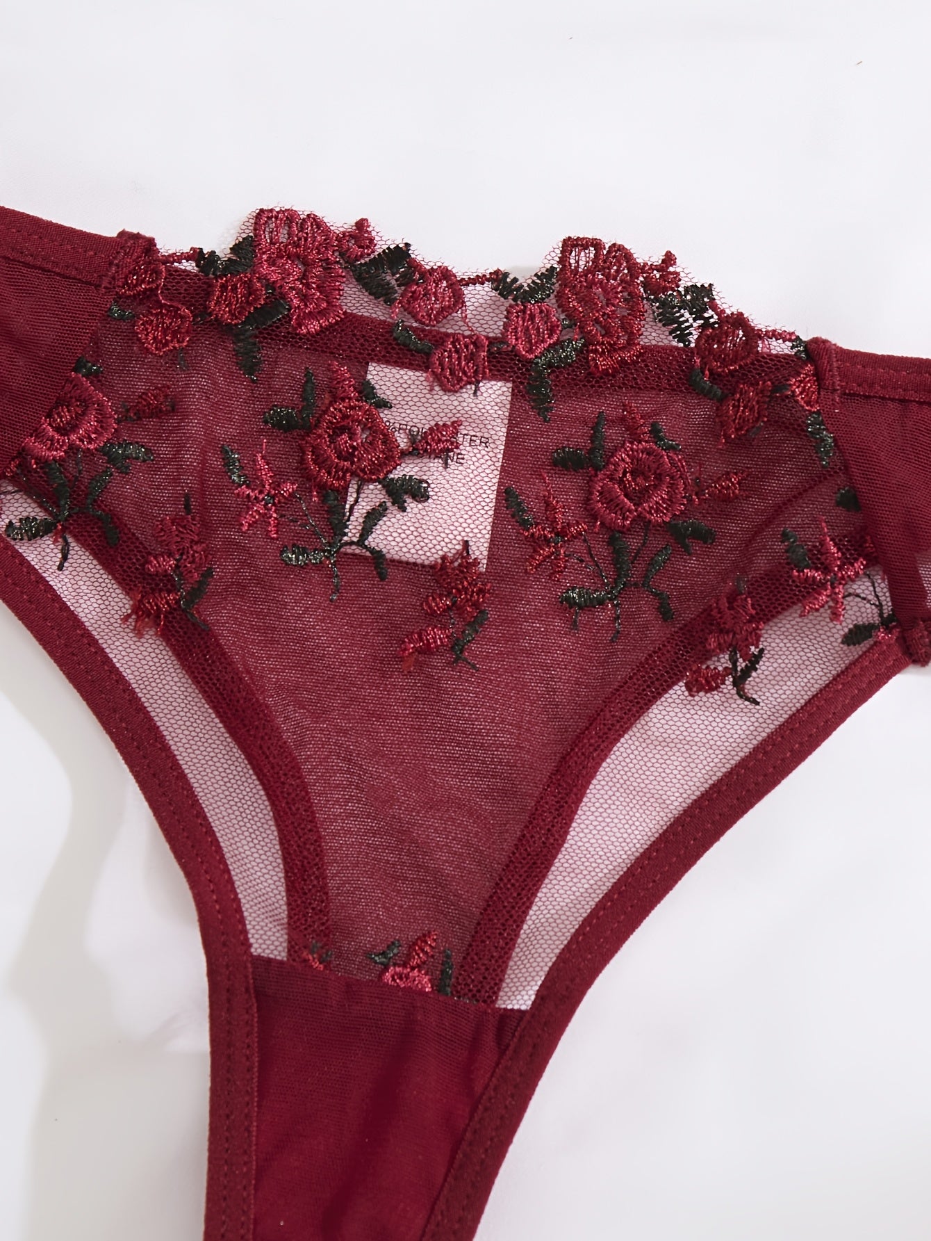 Red floral embroidered lingerie set for women with sheer mesh bra and low-rise panties. Hand washable, made from polyester and elastane blend.