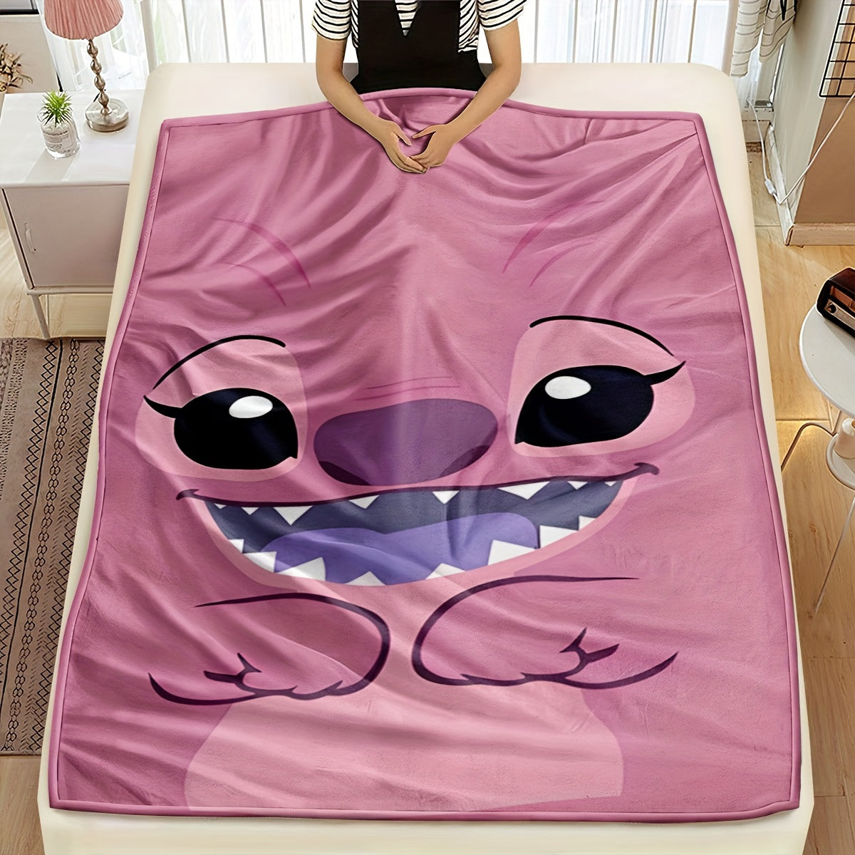 Pink plush throw blanket featuring a contemporary cartoon design. Made from soft polyester knit fabric, this multipurpose bedding is suitable for all seasons. Perfect for adding comfort to your bed, sofa, office nap, or as a travel blanket. Makes an