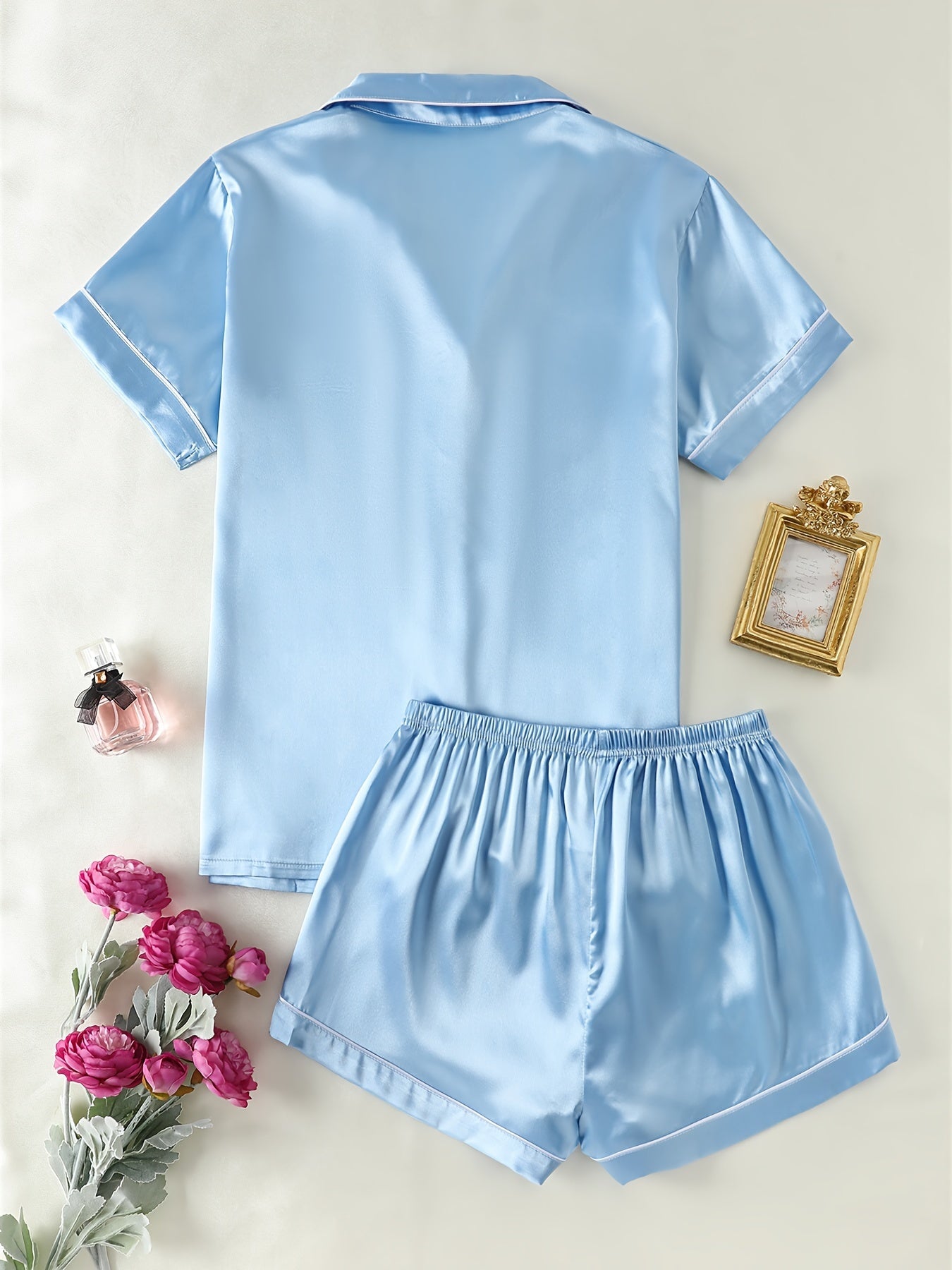 Satin lounge set includes a short sleeve button-up top with lapel collar and elastic shorts.