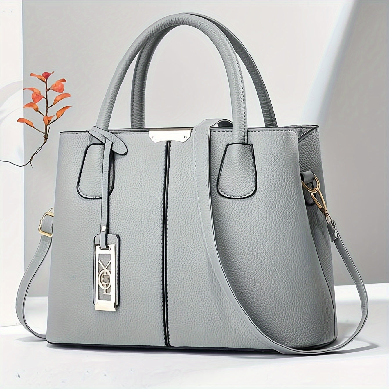 White synthetic leather tote bag with tag detail, versatile for dates, parties, and professionals. Large capacity with multi-layer design and strap closure.