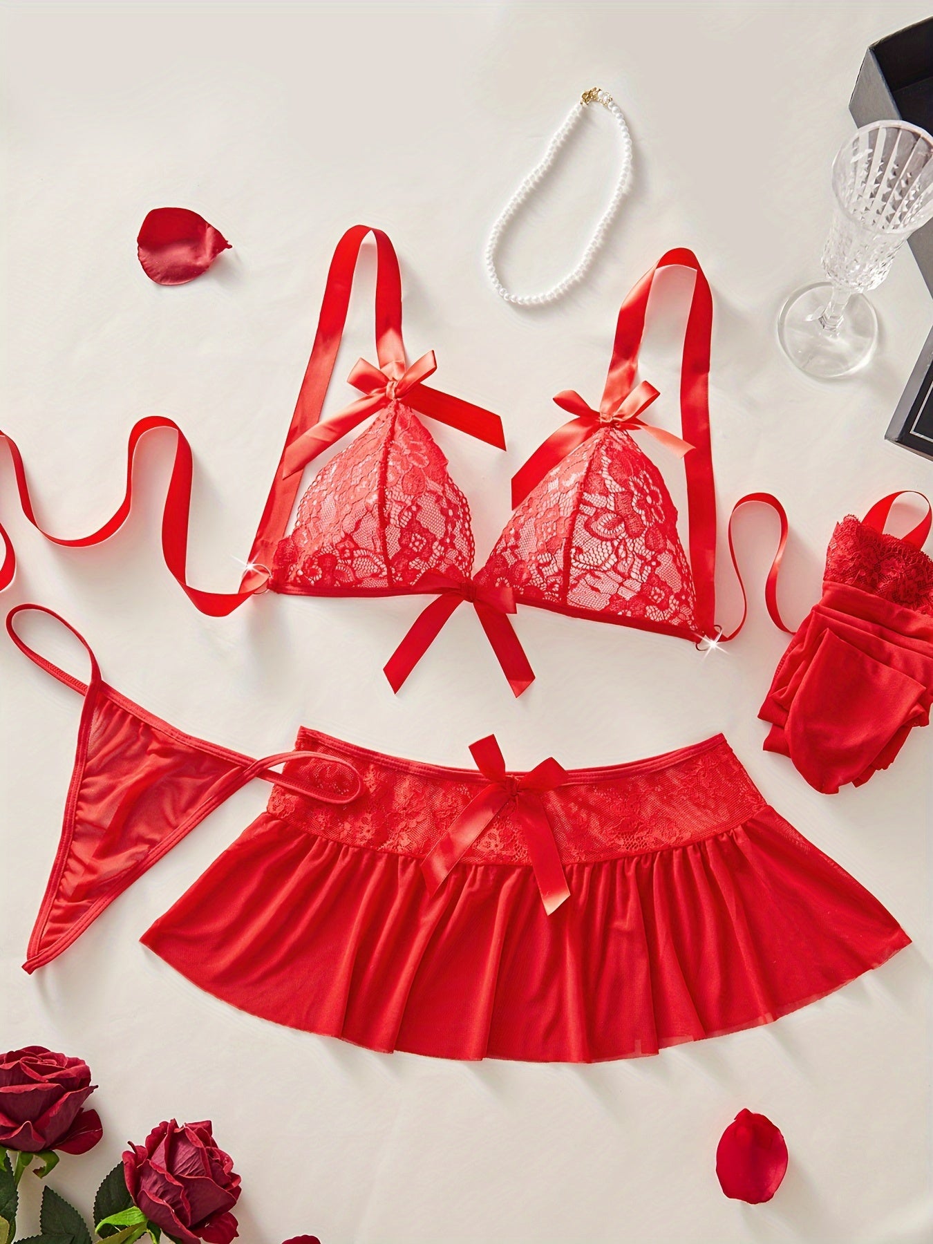 Red lace lingerie set with floral design and bow decorations includes bra, thong, mini skirt, and stockings for a sexy look.