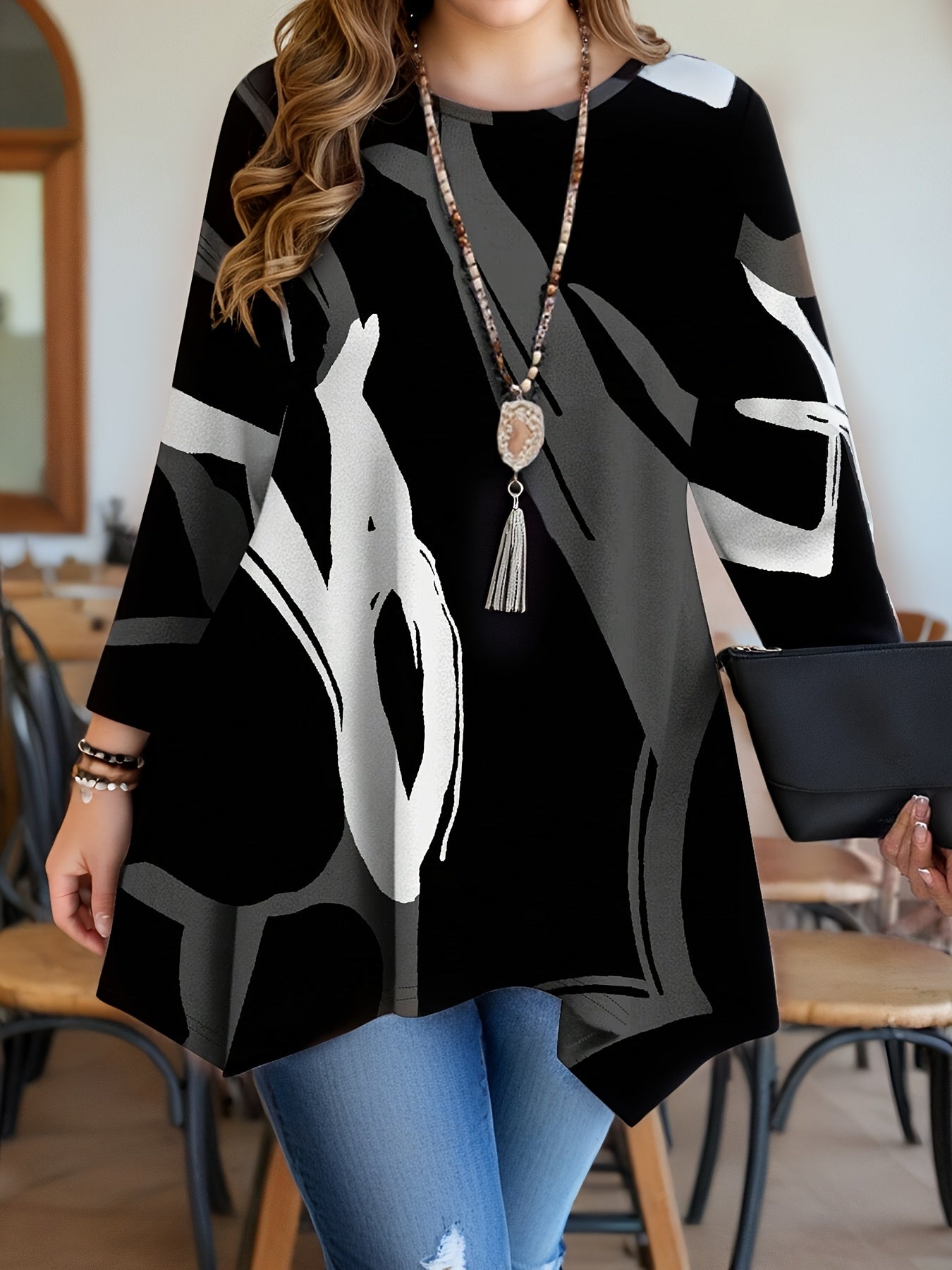 Women's plus size geometric print tunic top with asymmetrical hemline in black, red, white, and gray. Features long sleeves, round neck, and is machine washable. Made of polyester blend.