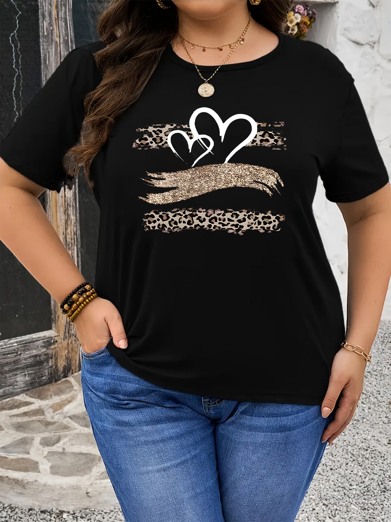 Plus size black T-shirt with leopard and heart print, made of stretchy polyester. Features a round neck, short sleeves, and is suitable for spring and summer wear.