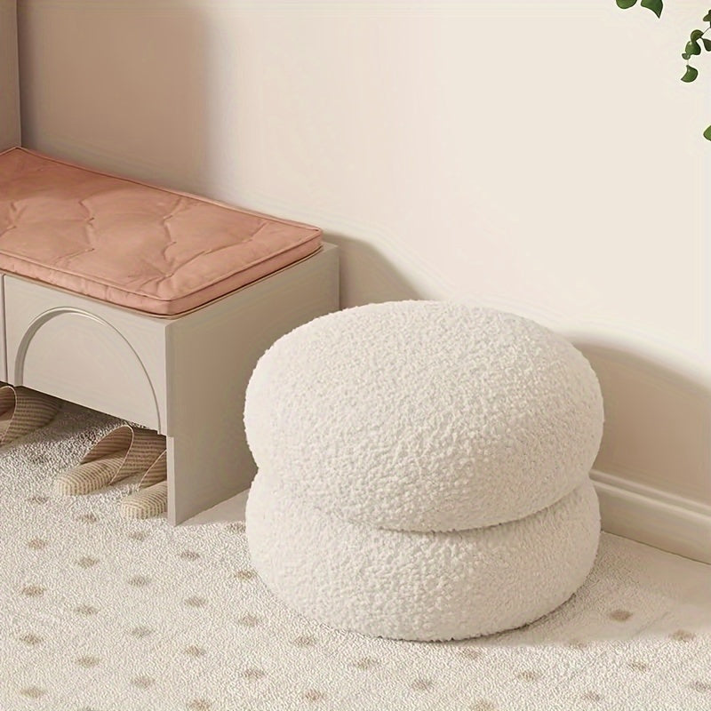 White polyester sofa stool that is versatile and compact. This round ottoman is ideal for the living room, great for changing shoes and enhancing home decor. Features a contemporary style.