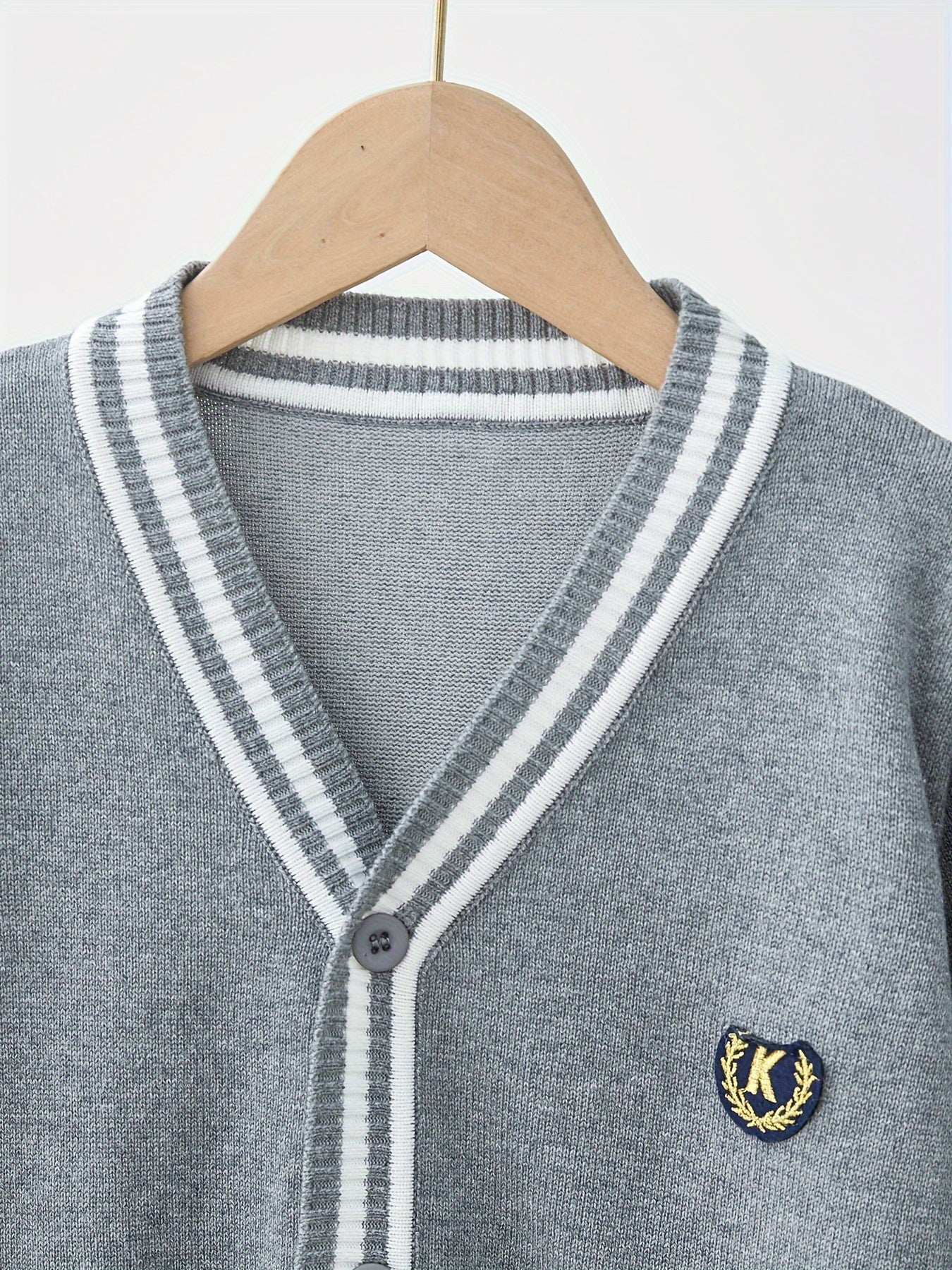 Youngsters' black and white striped V-neck cardigan with "K" logo, suitable for boys and girls in spring and fall. Perfect for school uniforms, stylish and versatile.