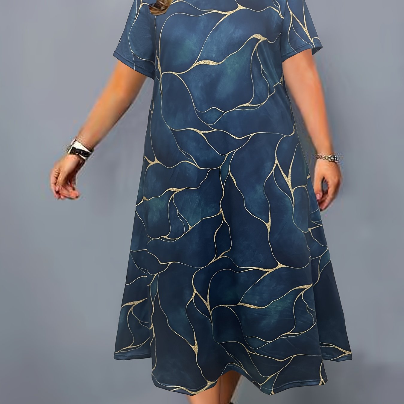 Flowy maxi dress with elegant blue and golden geometric print, round neck, and short sleeves. Made of stretchy, machine washable polyester blend. Perfect for spring/summer.