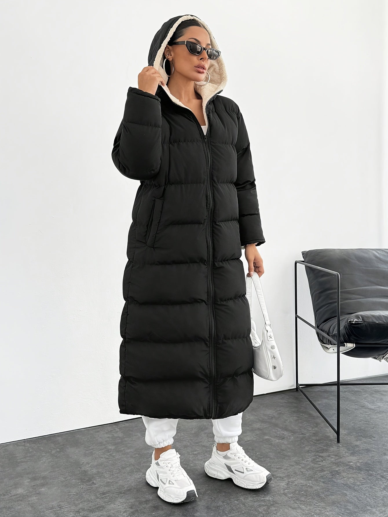 Black elegant long puffer coat for women, windproof with hood and side pockets. Made of machine washable polyester, perfect for cold weather outfits.