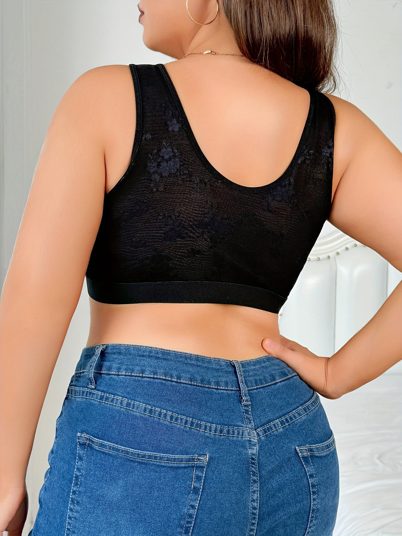 Lace-trimmed shapewear top for women with front closure. Medium support, non-padded. Polyester and elastane blend with a floral pattern in sleek black. Hand washable. Fashionable and