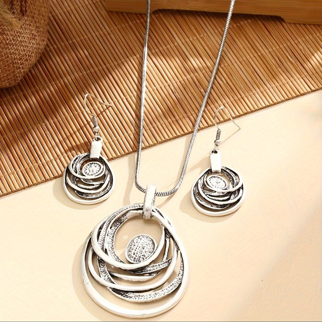 This set includes a pair of earrings and two necklaces made of zinc alloy in an ancient silvery color. The necklaces feature a multi-layer circular mosaic design with a retro bohemian style and a hollow center. This leisure jewelry set is perfect as a