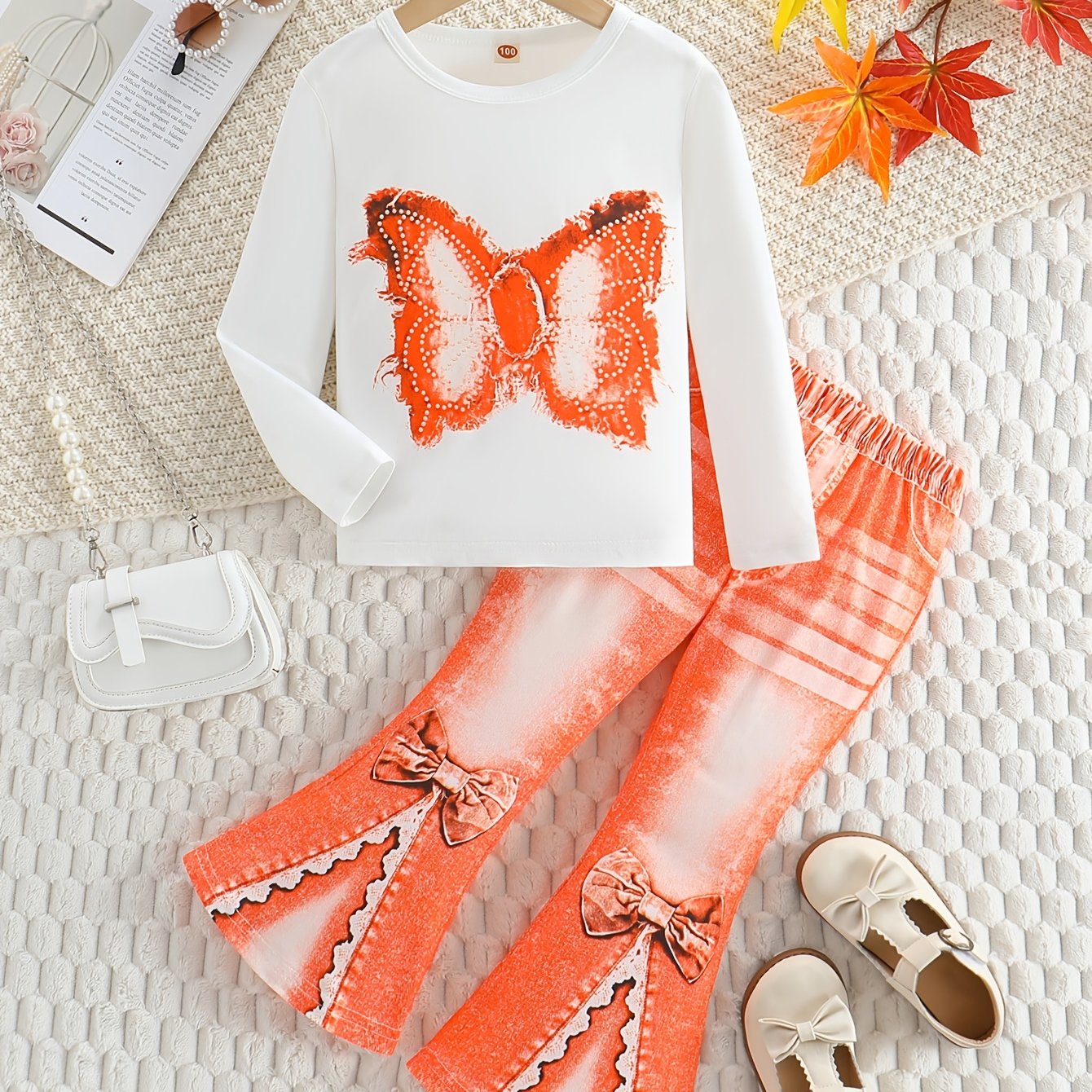 Girls' outfit set includes a long sleeve top with butterfly print and flared faux denim pants with a bow detail. Made of slight stretch knit fabric with an animal pattern, this regular fit