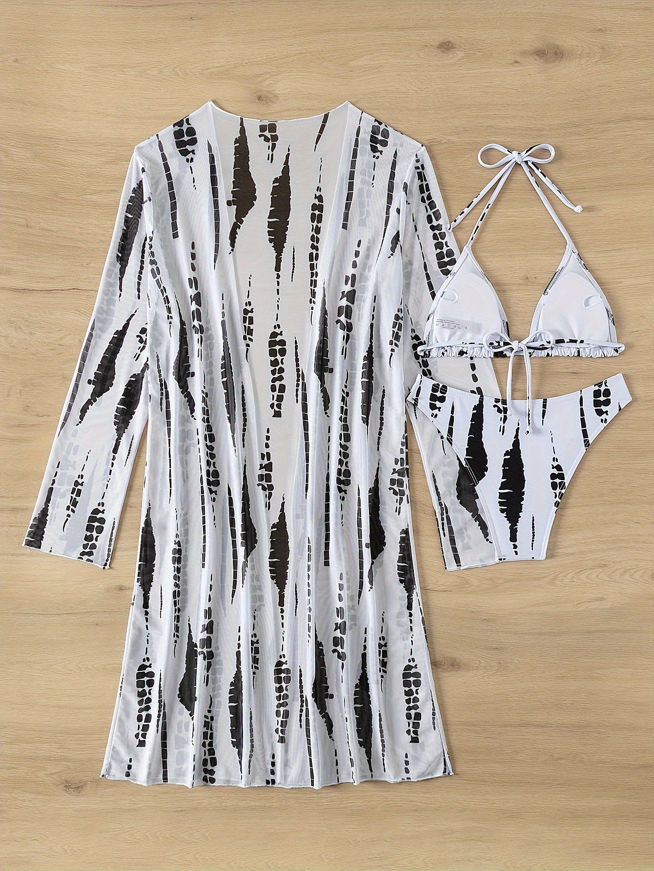 Women's strapless bikini set with long sleeve cover-up made of high stretch polyester and elastane. Features a random print, cross strap detail, swimwear with shorts bottom. No belt