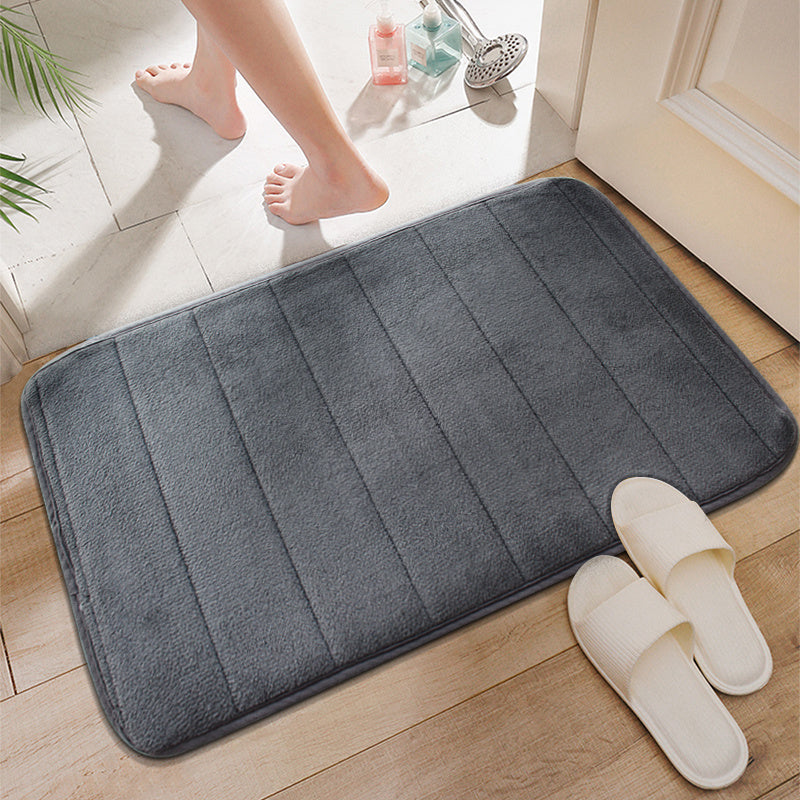 Soft polyester blend bath mat in plush dark gray stripes, featuring a non-slip PVC backing for added safety. Easily machine washable for convenience, this rectangular mat is perfect for adding comfort to your bathroom décor.