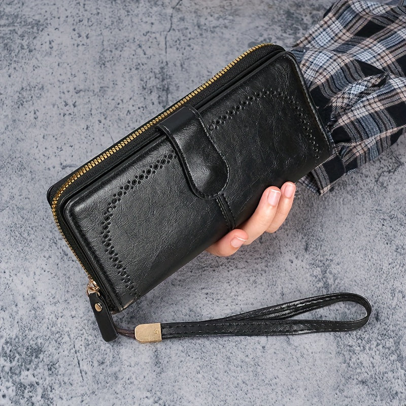 Black faux leather long clutch wallet with wristlet, ID card compartment, button closure, and edge paint. Dry clean only.