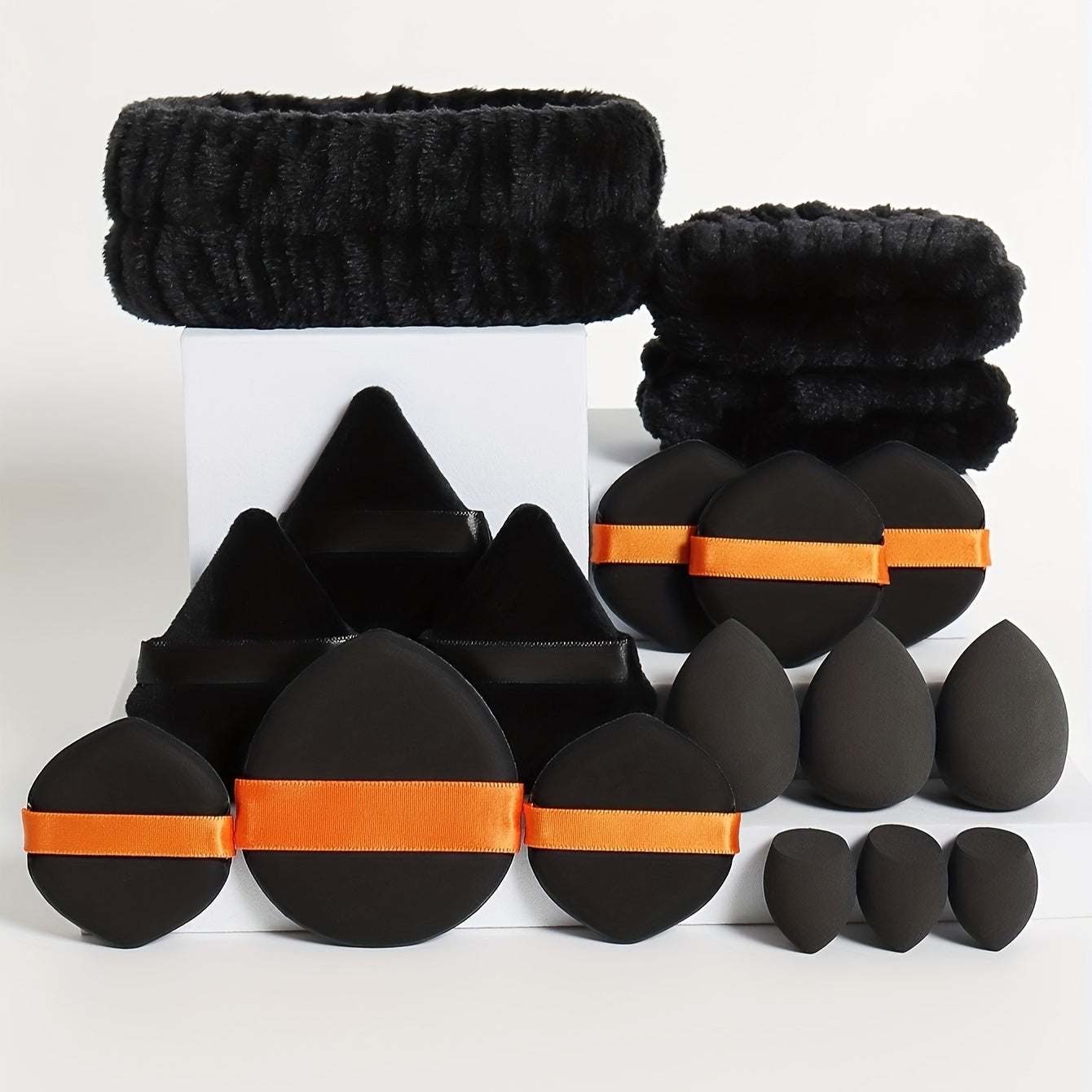 18-piece set including 1 hairband, 2 wristbands, 3 makeup sponges, 3 mini makeup sponges, 3 loose powder puffs, and 6 air cushion puffs. Features foundation mixing sponge for flawless