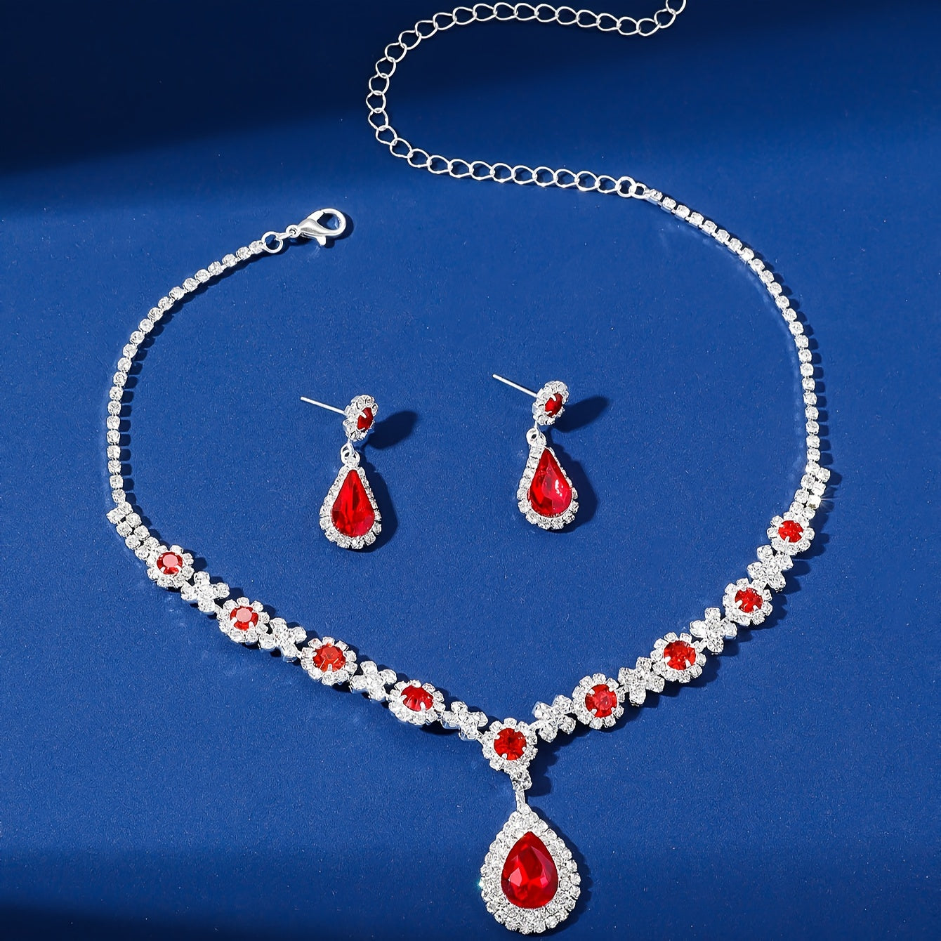 Stylish and opulent silver plated necklace and earrings set adorned with red rhinestone flower detailing and teardrop pendants. This elegant copper fashion jewelry set is designed for women, ideal for parties, banquets, and Valentine's Day. A versatile