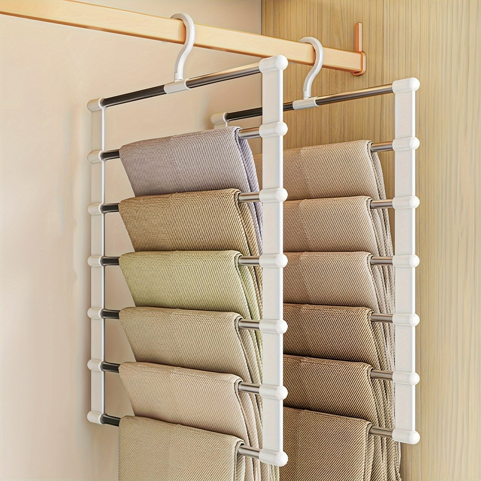 Multi-layer pants hanger made of stainless steel with folding design and white plastic end caps for space-saving storage and organization of clothes.