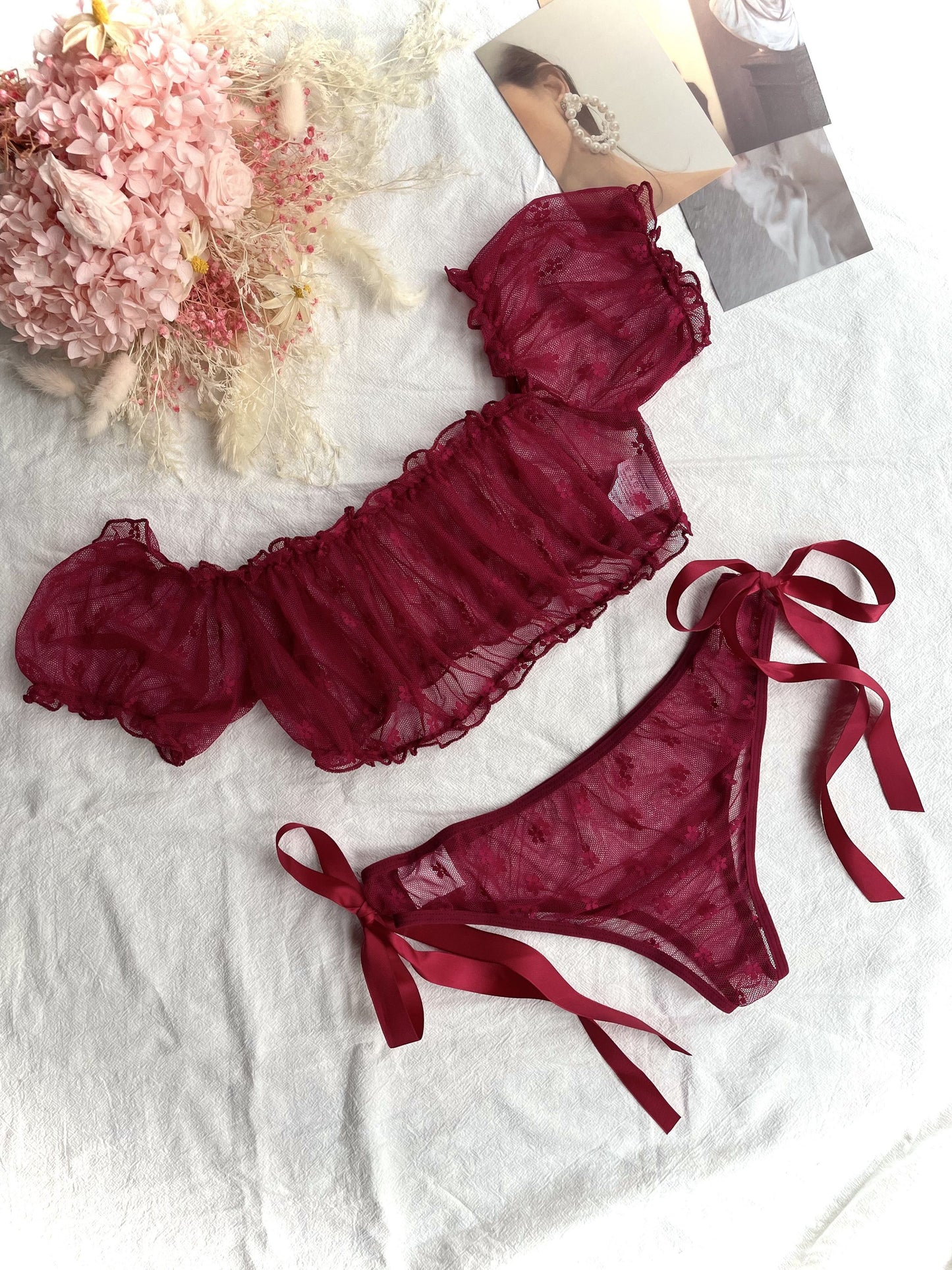 Red lace lingerie set with off-shoulder bra and low-rise panties for women.