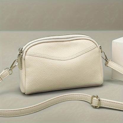 Women's genuine leather crossbody bag - solid color with adjustable strap, zipper closure, and polyester lining.