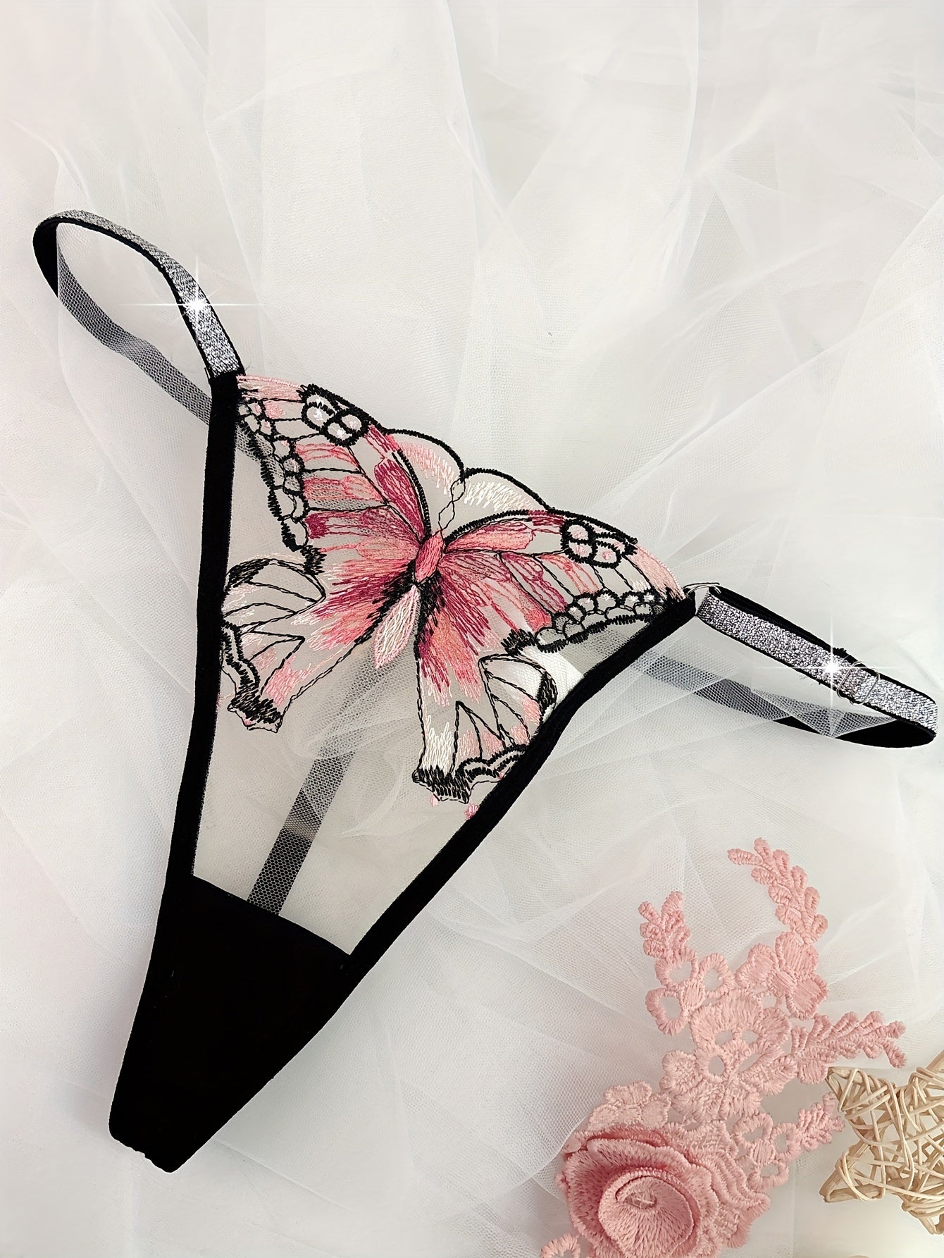 Hand-washable purple thong with butterfly embroidery and glitter trim, made of semi-sheer polyester blend.