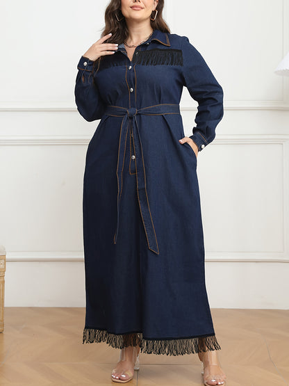 Women's plus size navy blue denim dress with long sleeves, button-up shirt collar, fringe hem, belt detail, and cotton/polyester blend. Machine washable.