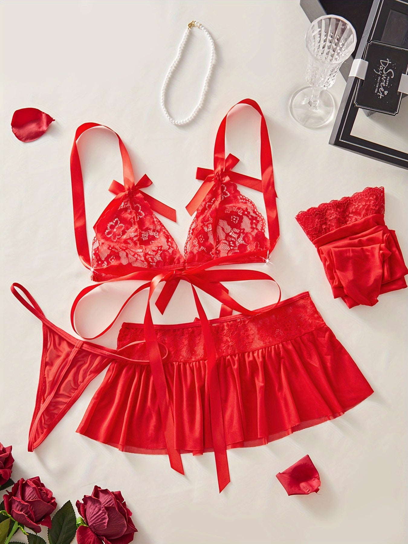 Red lace lingerie set with floral design and bow decorations includes bra, thong, mini skirt, and stockings for a sexy look.