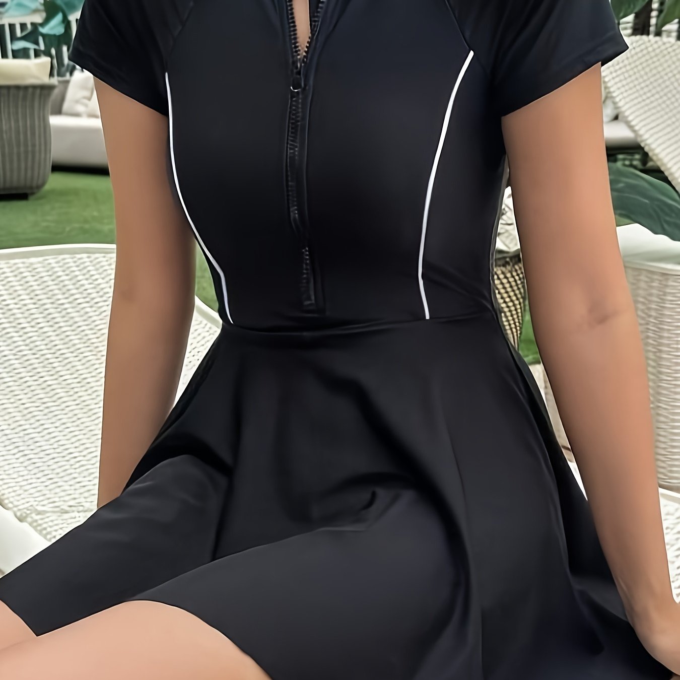 Sporty black one-piece swimsuit for women with zipper detail, made from high stretch nylon/elastane blend. Features short sleeves, round neck, and non-transparent fabric suitable for