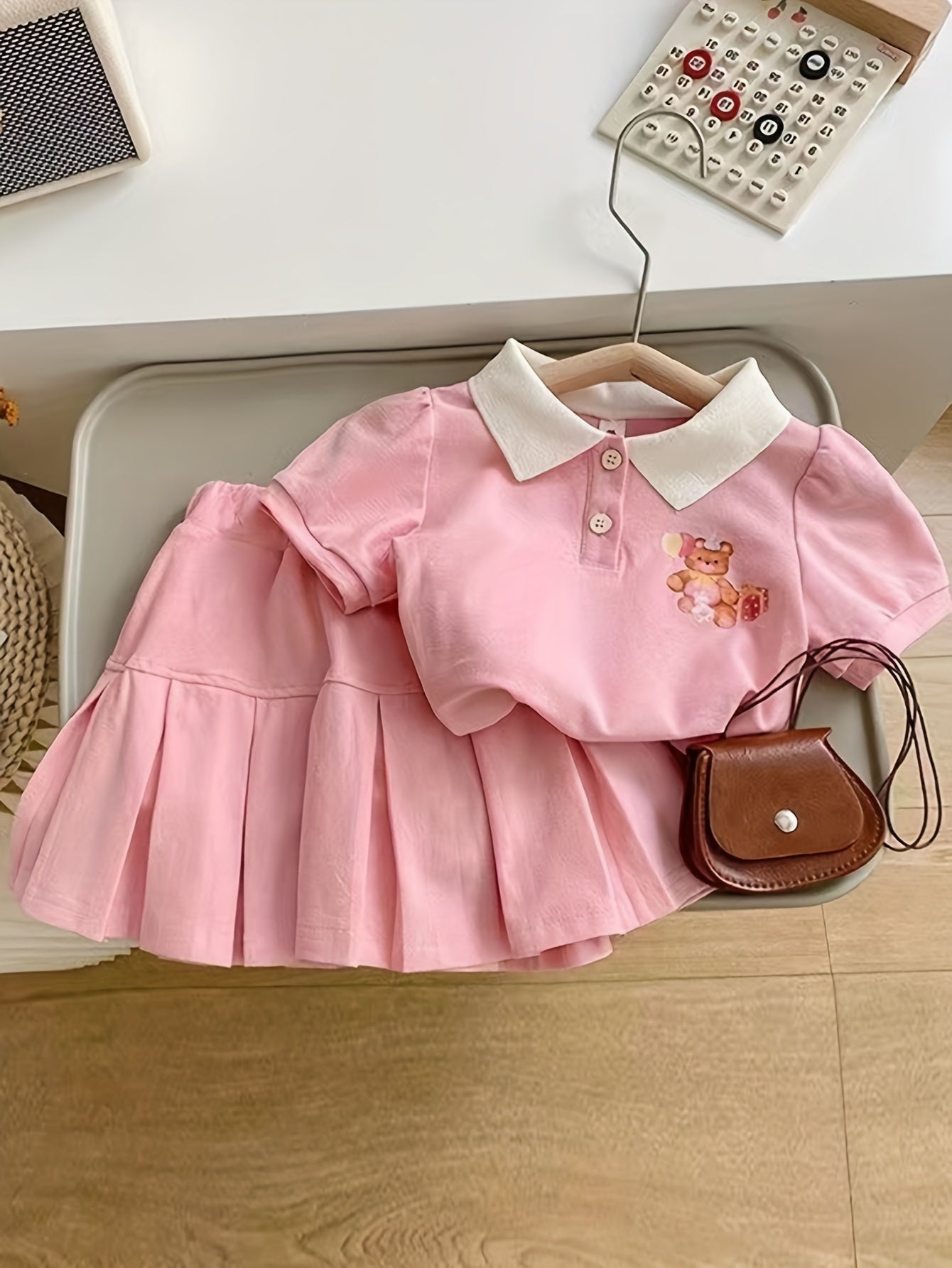 Pink floral short-sleeve collared top and pleated skirt set for charming girls, made from cotton blend fabric, ideal for casual wear in summer.